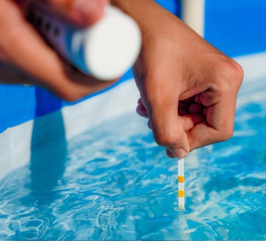 Pool water testing strip dipped into swimming pool