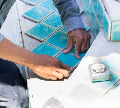 Man installing tile on swimming pool